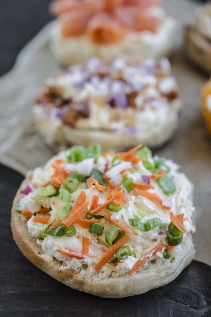 Two bagels with different toppings on them.