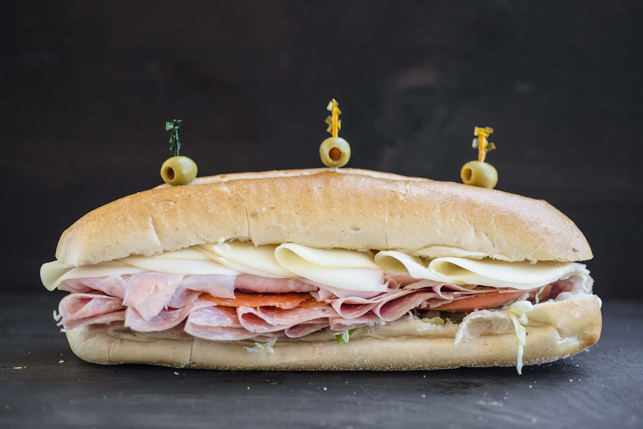 A sandwich with ham, cheese and mustard on it.