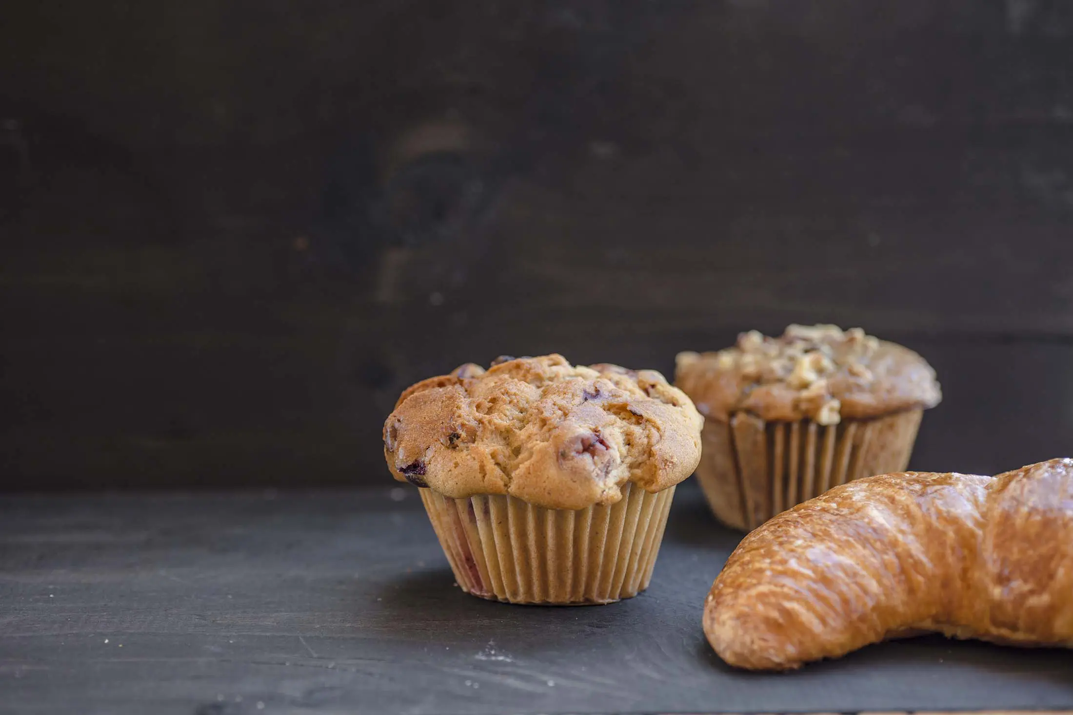 A muffin and two other pastries on a table.