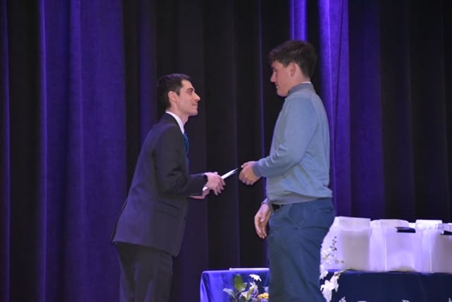 A man and woman shaking hands on stage.