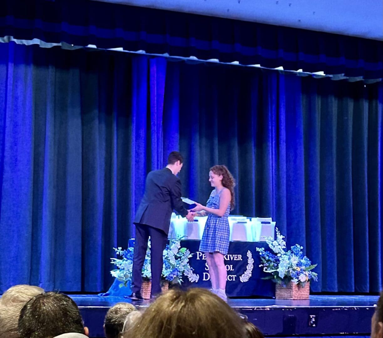 A man and woman are shaking hands on stage.