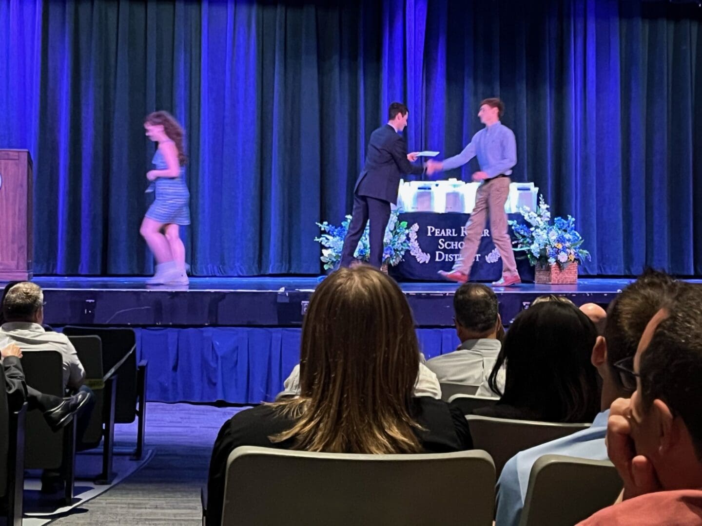 A man and woman on stage shaking hands.